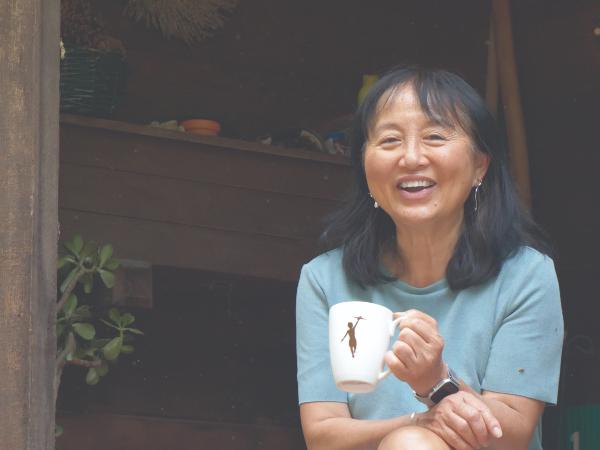 A smiling woman in her fifties holding a mug.