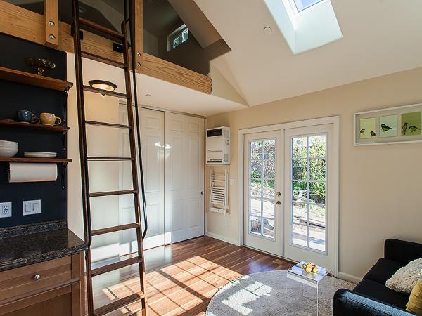 Interior of an ADU with high-ceiling, lots of natural light, a ladder leading to a loft bed.
