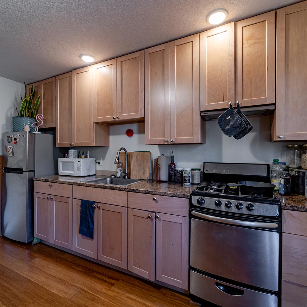 Kitchen inside of junior ADU with fridge, microwave, sink, oven and many cabinets.